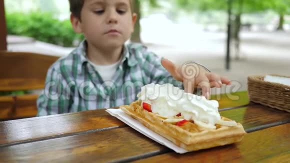 垃圾食品小孩用奶油舔手指在户外咖啡馆品尝甜点视频的预览图