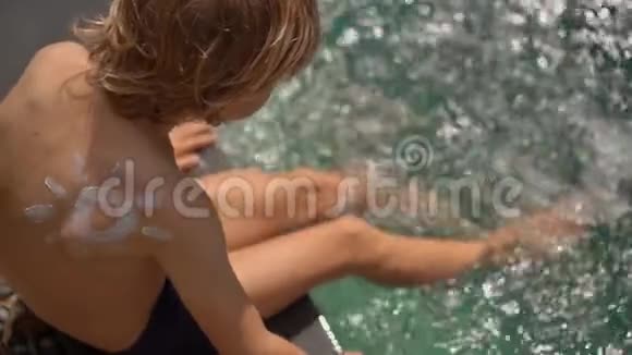 一个小男孩在游泳池里用防晒霜晒太阳动作缓慢视频的预览图