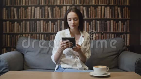 美丽的女人在咖啡馆里喝咖啡看书视频的预览图
