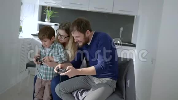 现代家庭妈妈和儿子爸爸坐在椅子上玩电子游戏视频的预览图