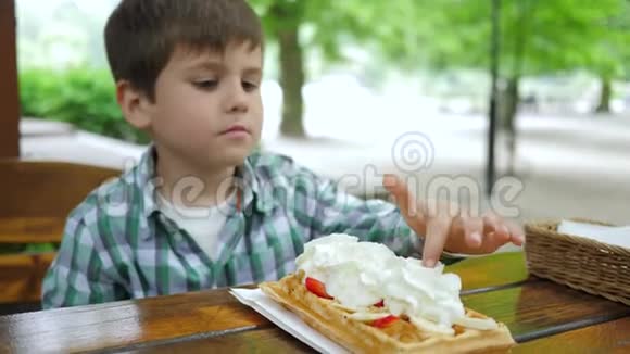 咖啡馆里的孩子吃盘子里的圆片奶油在餐桌上品尝甜点视频的预览图