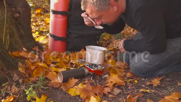 在秋天的森林里烧煤气游客试着从锅里取出食物视频的预览图