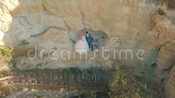 新婚夫妇一起在山坡上可爱的新郎和新娘日落从空中射击视频的预览图