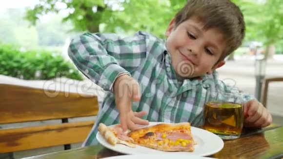 咖啡馆里饥饿的孩子坐在一张桌子旁吃披萨桌上放着一杯果汁视频的预览图