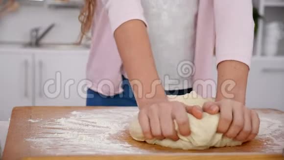 小女孩用手在厨房的木板上揉面团视频的预览图
