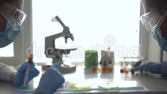 科学家一男一女对培养皿进行化学实验并在实验室的注射器中取样视频的预览图