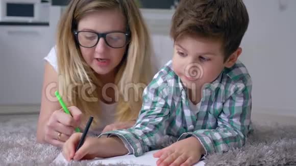 学前教育有孩子的女人在度假时躺在地板上用彩色毡尖笔画视频的预览图