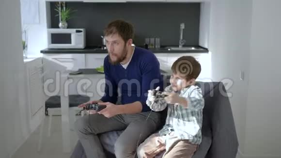 家庭娱乐年轻爸爸带着孩子在家玩电子游戏视频的预览图