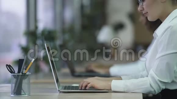成功的女性在笔记本电脑上输入电子邮件微笑的女性在办公室享受工作视频的预览图