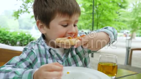 有害的食物五岁的男孩在户外的一张桌子上坐着一片比萨饼视频的预览图