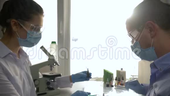 实验室助理团队在工作时间在明亮的光线下用手中的试剂做化学实验视频的预览图