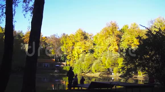 秋天在城市公园一个美丽的池塘附近休息的家庭视频的预览图
