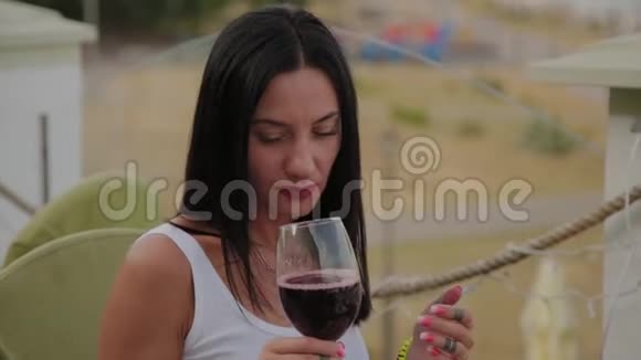 漂亮的女人在餐馆的露台上喝红酒视频的预览图