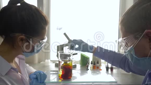 科学家在医学实验室的工作场所用明亮的光线混合大玻璃中的颜色试剂视频的预览图