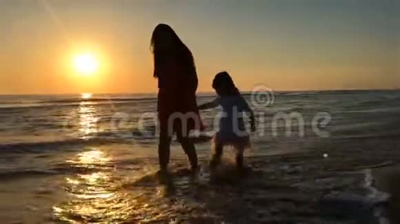 在海边散步的母亲和孩子的剪影视频的预览图