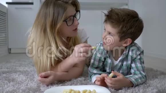 甜甜的牙齿带着妈妈的小男孩戴着眼镜在房间里吃着盘子里的饼干视频的预览图