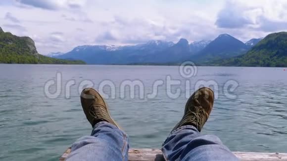 山湖和白雪覆盖的山脉背景上的人类腿视频的预览图