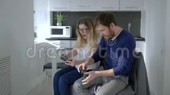 年轻夫妇坐在沙发上玩电子游戏互相推搡视频的预览图