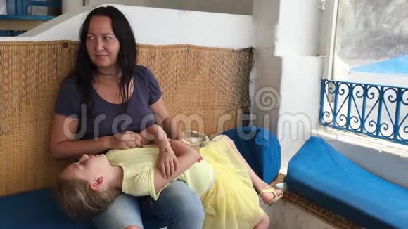 年轻的母亲抚摸着生病的肚子女儿躺在她的腿上视频的预览图