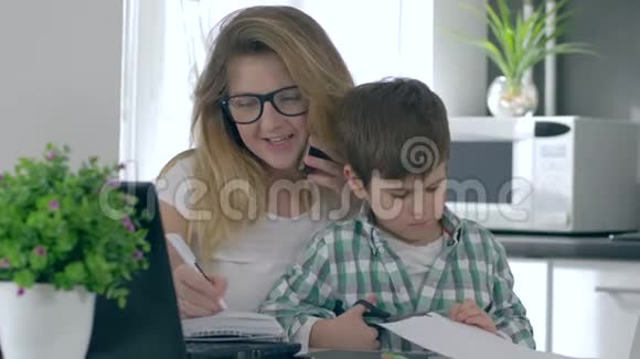 有儿子在手的商务女性同时使用笔记本电脑和手机做很多工作视频的预览图