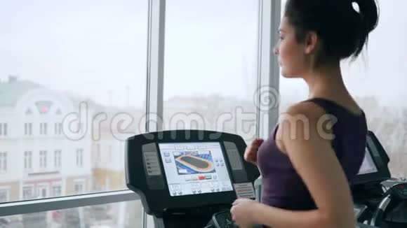 在健身室训练期间可爱的女性在跑步模拟器上喝凉水视频的预览图