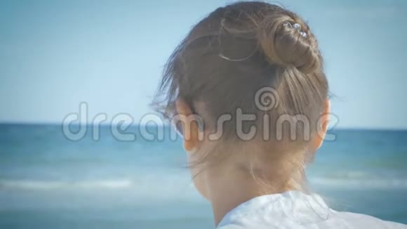 穿着白色衬衫的女孩摘下太阳镜环顾四周微笑着坐在海滨特写视频的预览图