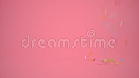 洒在粉色背景上蛋糕和面包房装饰慢动作视频的预览图