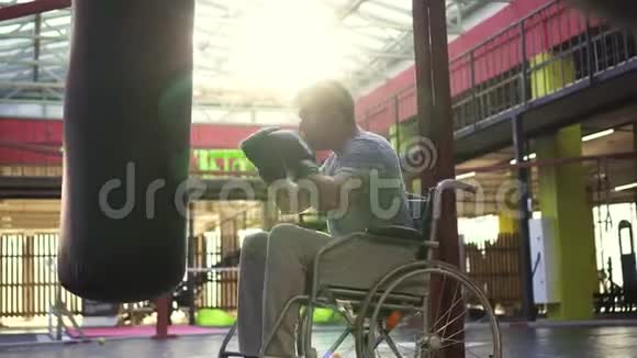 一个坐轮椅的残疾人在健身房里用手套敲打一个拳击袋视频的预览图