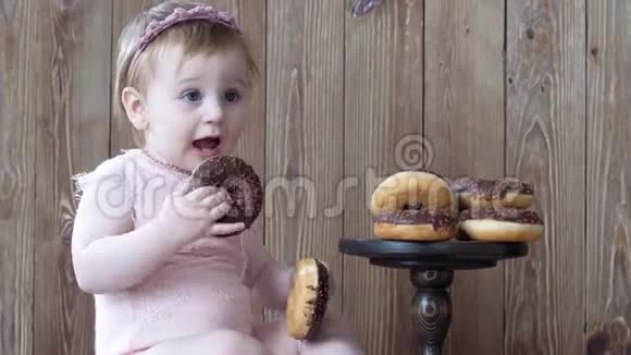 快乐的童年婴儿在木墙上吃甜甜圈视频的预览图