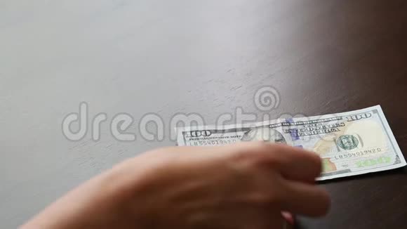 女人数着100美元的钞票摆在桌上视频的预览图