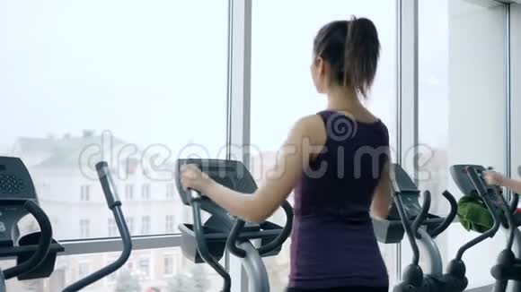 有魅力的女性在带有全景窗的健身房锻炼体育器材视频的预览图