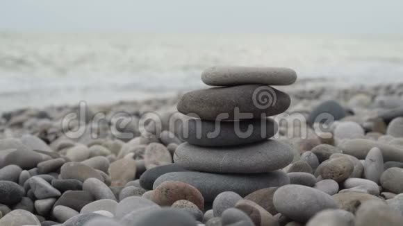 女人用手在海滩上堆石头视频的预览图