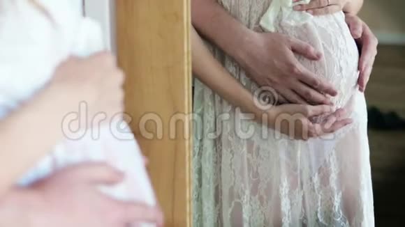 丈夫在特写镜前拥抱怀孕的妻子男性手在镜子反射中抚摸怀孕的腹部视频的预览图