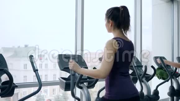 运动女孩在有大窗户的健身房运动模拟器上训练腿部肌肉视频的预览图