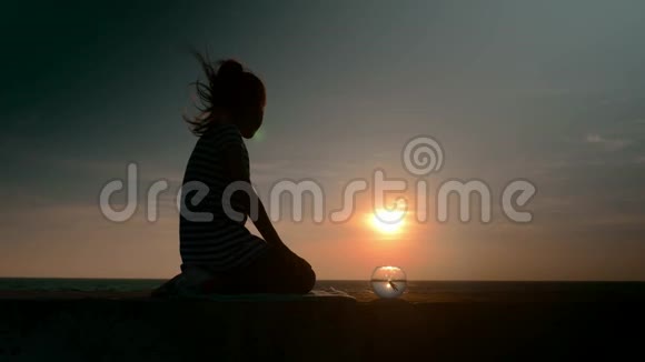 美丽的田园风光坐着小女孩她的剪影和圆形水族馆浮鱼在户外的海洋背景下视频的预览图