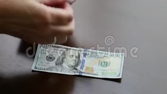 女人数着100美元的钞票摆在桌上视频的预览图