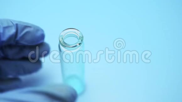 双手医生戴着乳胶手套把蓝色的液体从一个瓶子倒进另一个瓶子视频的预览图