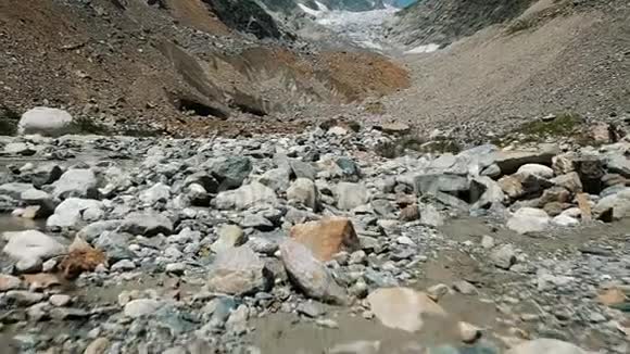 石碛在山上的冰川背景上缓行山溪和野花相机视频的预览图