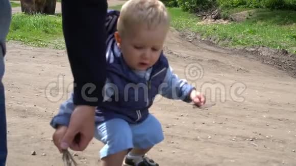 快乐的小男孩在公园里爸爸的帮助下迈出第一步视频的预览图