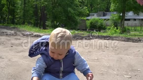 快乐的小男孩从公园的地上捡起一根树枝视频的预览图