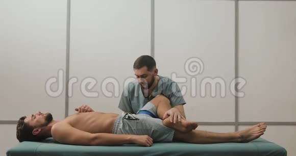 物理治疗师与男性患者一起工作他在医院的床上给男性病人做伸展运动视频的预览图