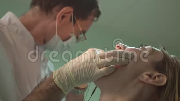 男牙科医生戴防护面罩治疗女病人牙齿视频的预览图