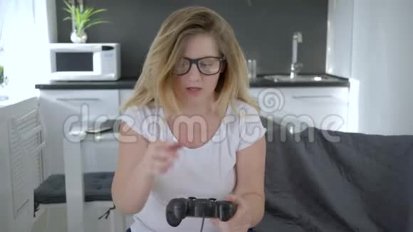 情感游戏玩家女人在家玩现代技术坐在房间的沙发上视频的预览图