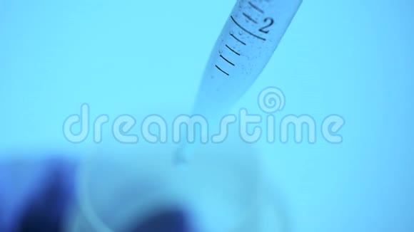 在实验室里一位拿着吸管的科学家从试管中分析了一种蓝色的彩色液体视频的预览图