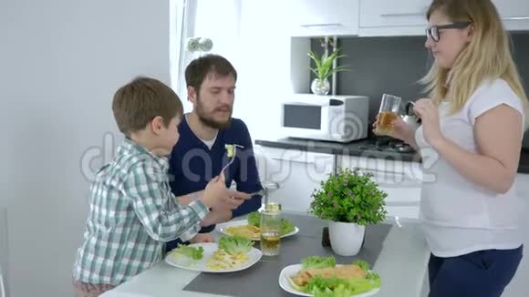 家庭早餐年轻的父亲和儿子同时喂母亲在室内欢笑视频的预览图