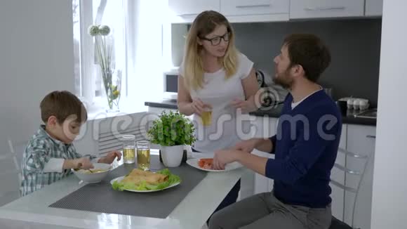 幸福的家庭在明亮的厨房里用鸡蛋和香肠做早餐视频的预览图