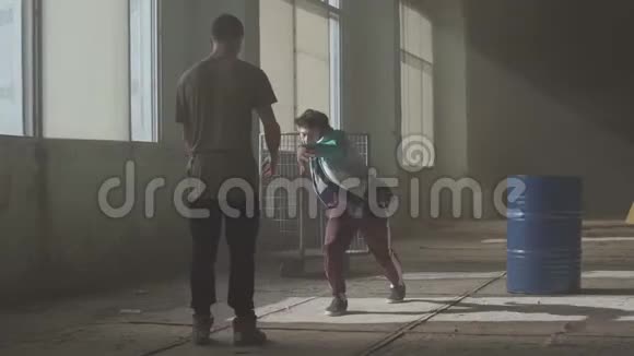 嘻哈文化排练当代的两名街头舞者在木桶附近的废弃建筑中的舞蹈战斗视频的预览图