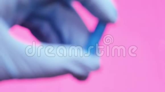 一只戴着蓝色医用手套的手拿着一个蓝色药丸胶囊视频的预览图
