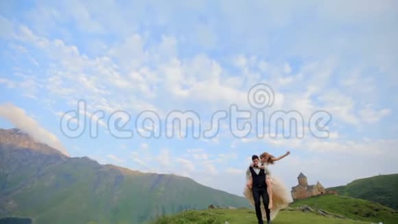 新娘和新郎在他们婚礼的那一天在一个晴朗的夏天在蓝天白云下玩得很开心视频的预览图