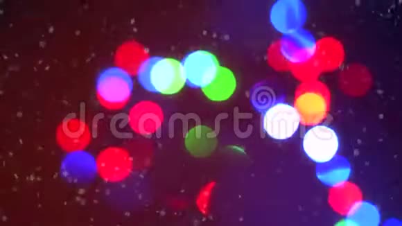 特写彩色闪烁的圣诞花环灯光背景被飘落的雪花包围视频的预览图